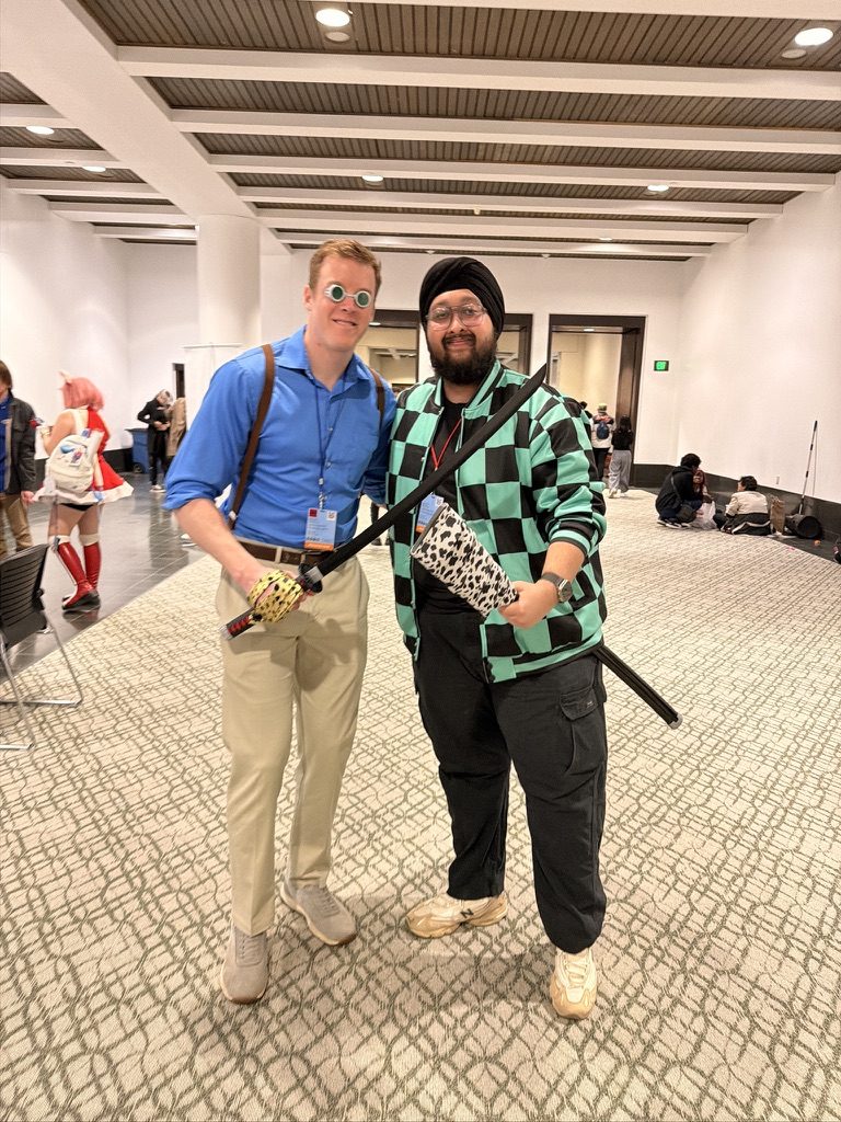 Dave in a green checkered costume with a sword next to a man in a blue shirt