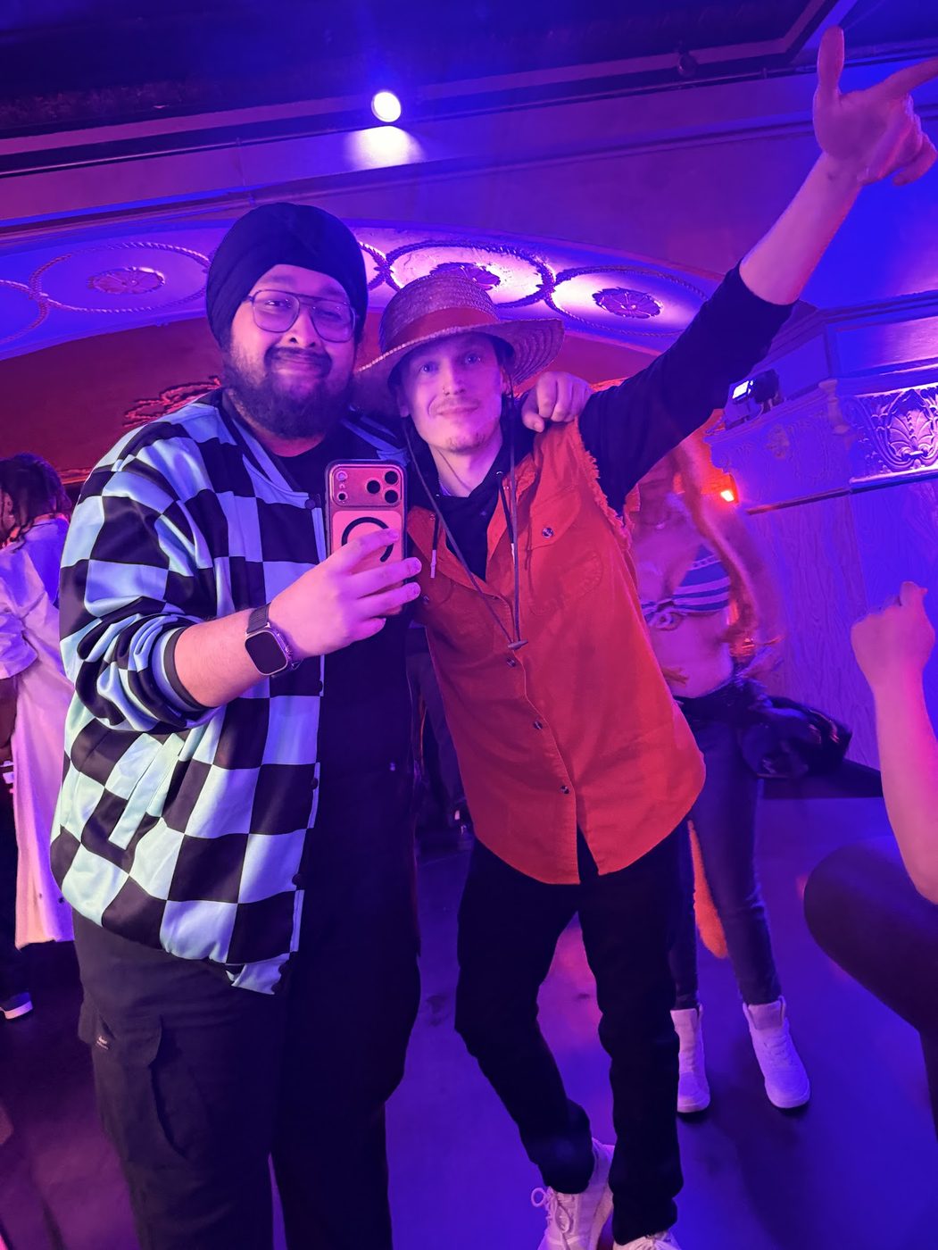Dave taking a selfie in costume with a friend under purple lights