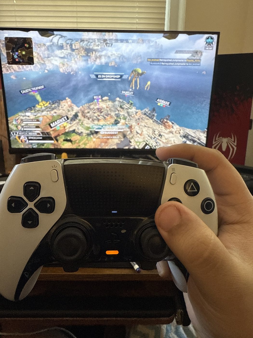A game controller held in front of a monitor showing a game