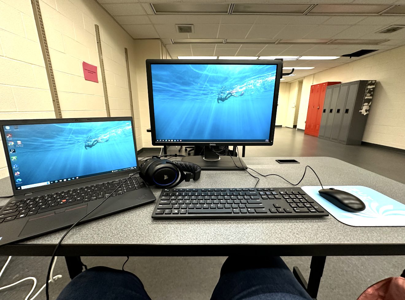A desk with a monitor and laptop in a bright office