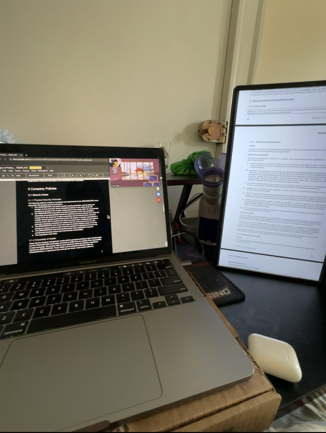 A laptop beside a tall monitor showing text