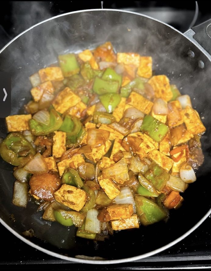Paneer and bell peppers cooking in a pan