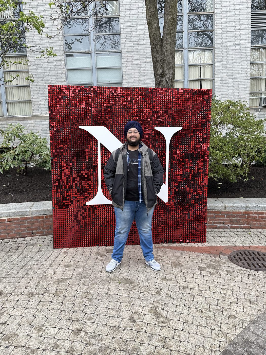 Dave standing in front of the red Northeastern N sign