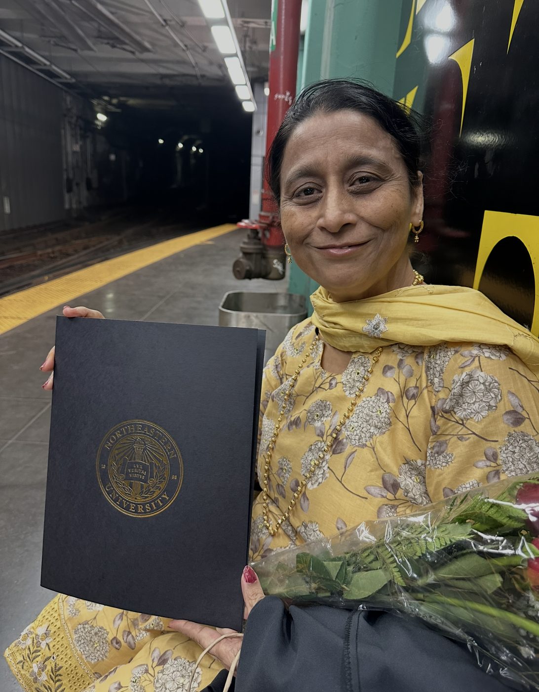 Dave's mom holding a diploma folder on a train platform