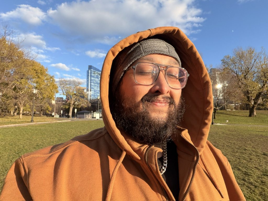 Dave in an orange hooded jacket on a sunny lawn