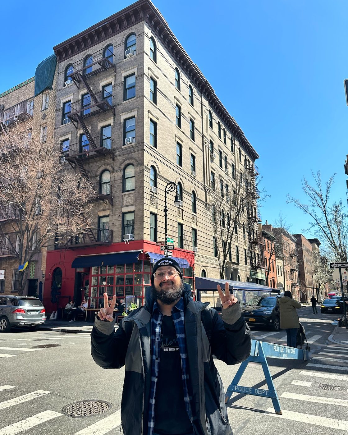 Dave posing on a city street in front of a brick apartment building
